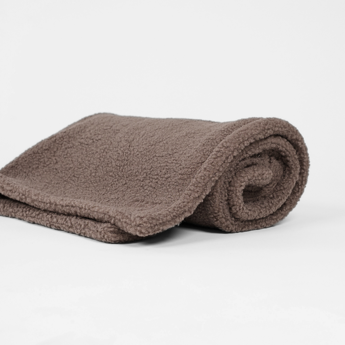 Taupe-värinen teddy-koiran viltti rullattuna