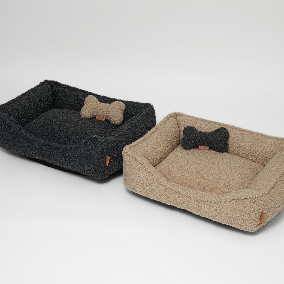 Two curly bouclé dog beds in storm and sand with bone-shaped cushions