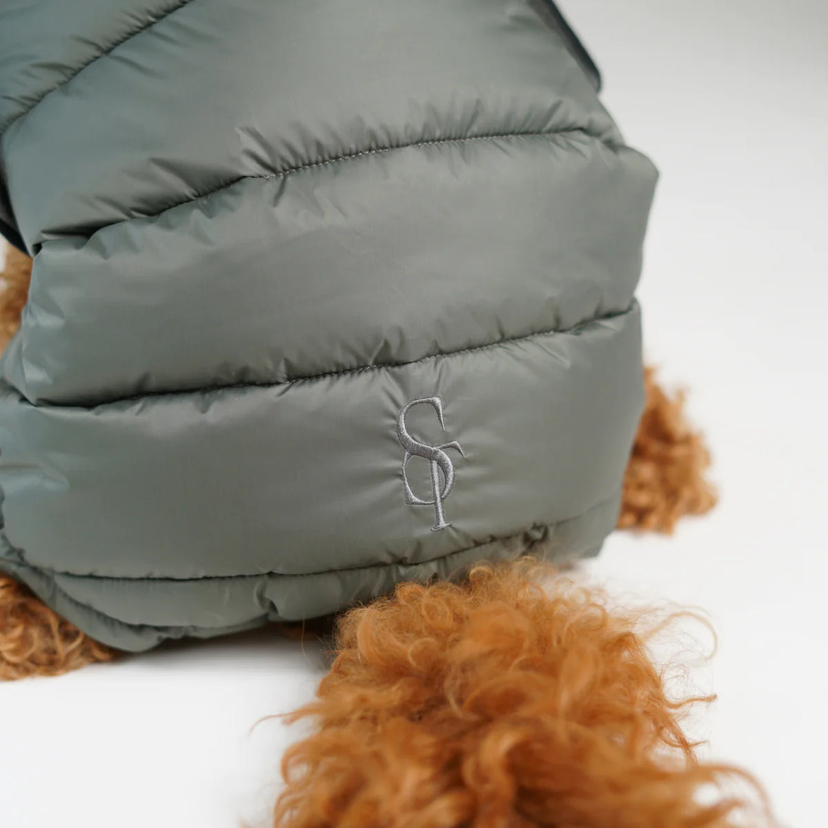 Lähikuva Moss Green -värisen tikkitakin kohokuvioidusta Staey-monogrammista